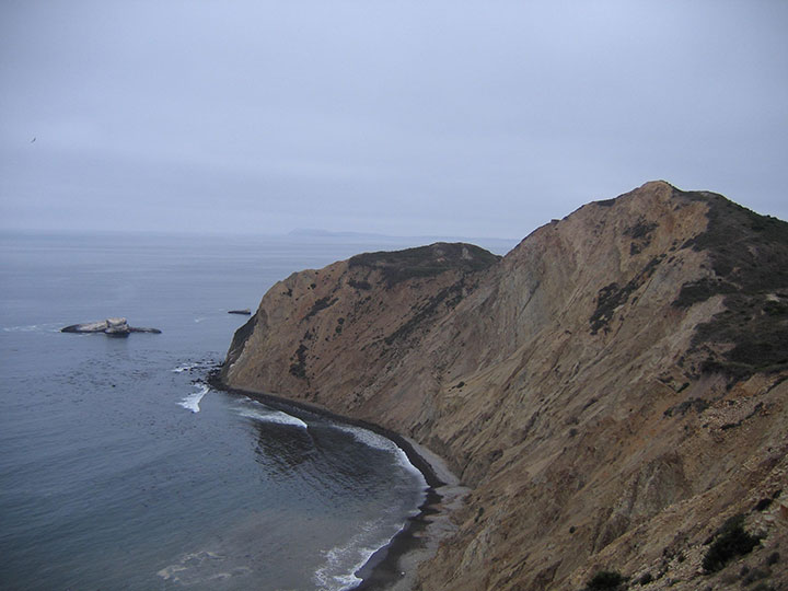steep rock hillside emerging from ocean