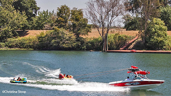 motorboat pulling people of floating watercraft in river
