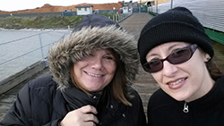 faces of two women, dressed for cold weather, on a marine dock