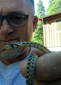 A small, thin snake held in the hand of a middle-aged man