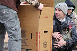 Man holding large cardboard box in front of man holding turkey.