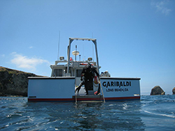 Scuba diver standing on stern of boat called the Garibaldi from Long Beach California