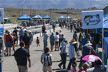 a crowd gathered around booths and hatchery ponds