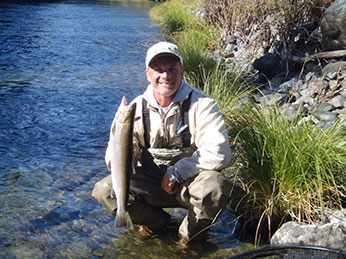 Angler with Steelhead sitting on the edge of river8