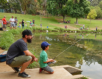child fishing with adult at urban pond