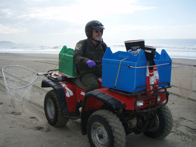man riding ATV carrying a net and several boxes