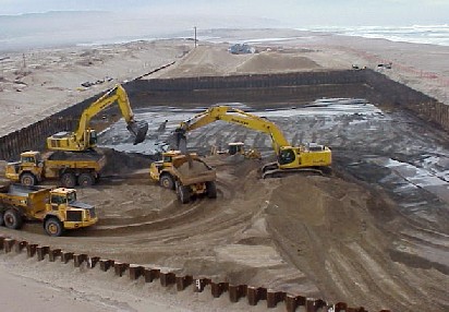 trucks and tractors moving contaminated sand