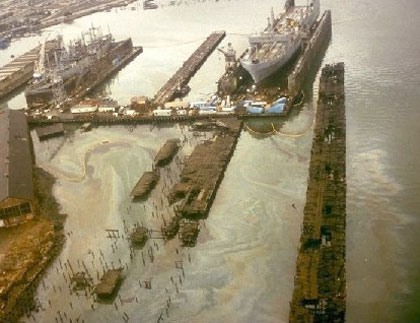 several ships in dock with very heavy oil sheen on the water